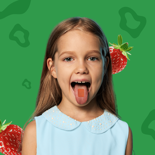 Young girl with a dissolvable vitamin strip on her tongue with strawberries on a green background