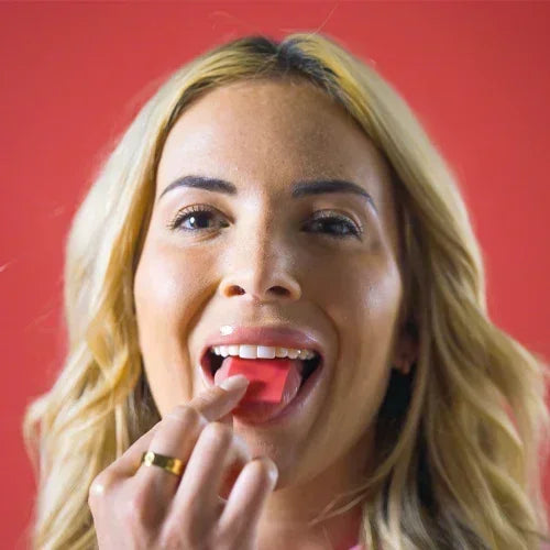 Woman applying Diso Strip on tongue against a red background